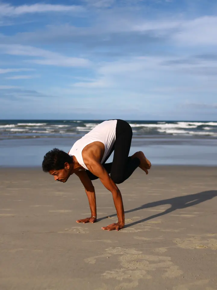 Arjun Mehta balancing in crow pose on a sandy beach